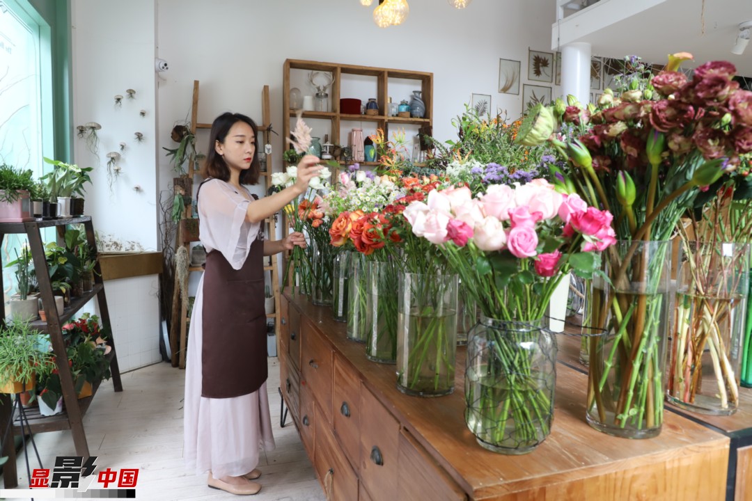 王黎媛是一名河南姑娘，在昆明念完大學(xué)后，就再也舍不下春城的藍天陽光、青山碧水，更舍不下這里的四時繁花，于是就干脆留了下來，成了一名媒體人。2017年的時候又毅然辭去工作，創(chuàng)業(yè)開起了花店，成了都市里的一名“花房姑娘”。圖為王黎媛在自己的花店中整理鮮花。新華網(wǎng) 周亞平/攝 念新洪/文